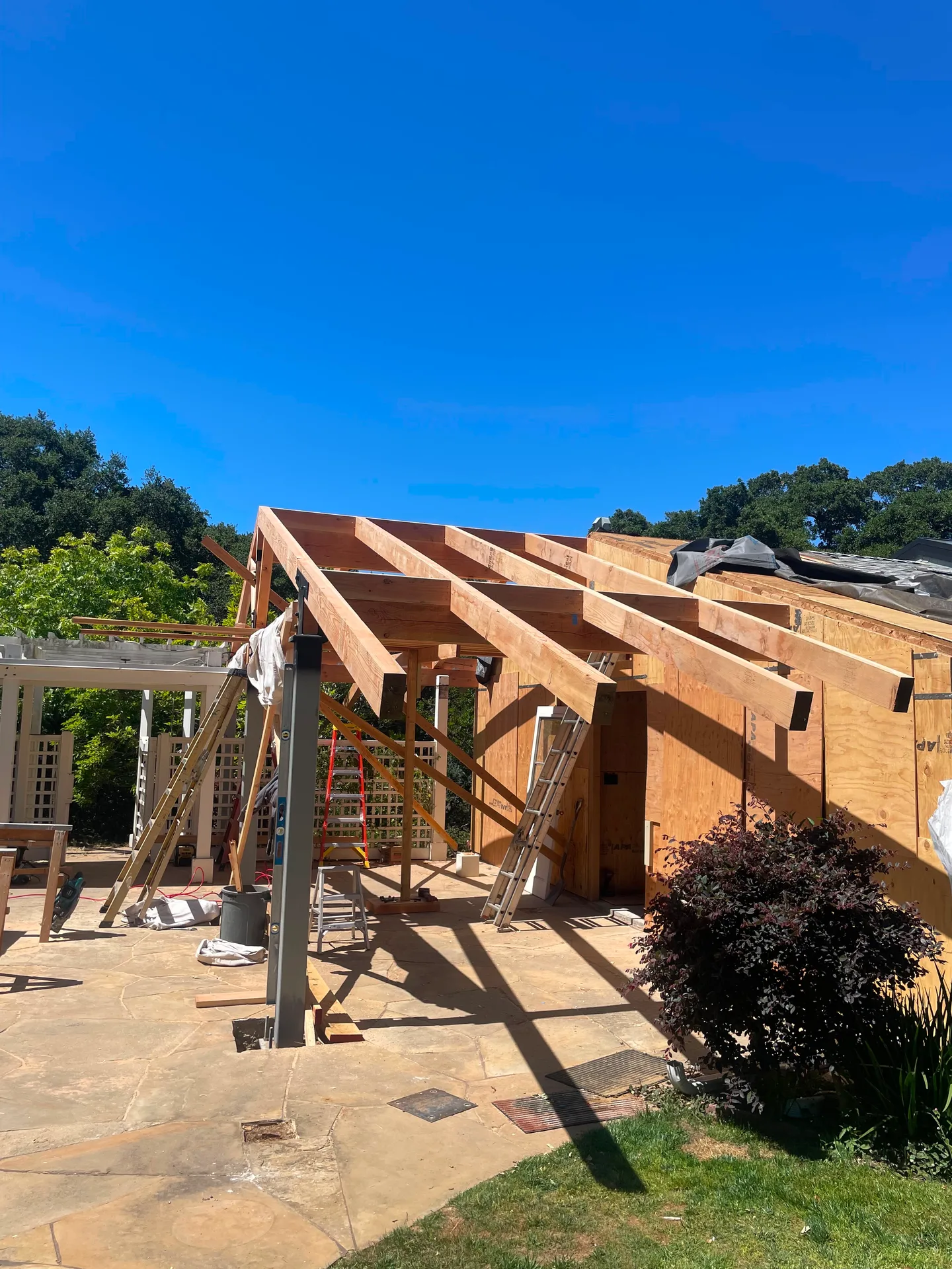 Patio cover roof framing against a blue sky